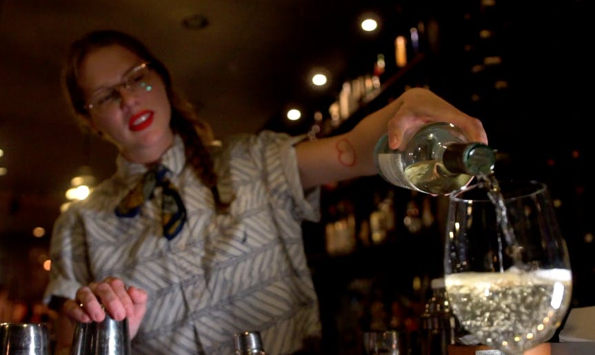 a person holding a bottle of wine serving wine in a glass